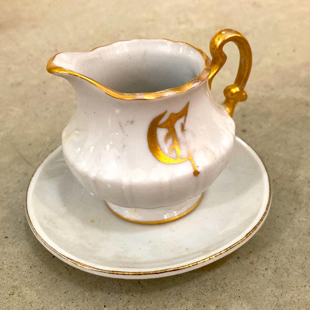Initial “ G “ gilt and white porcelain hand painted cream pitcher snd saucer.